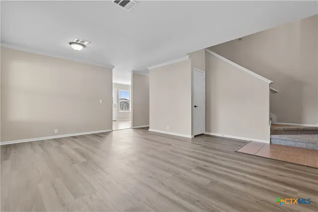 a view of an empty room with wooden floor and closet