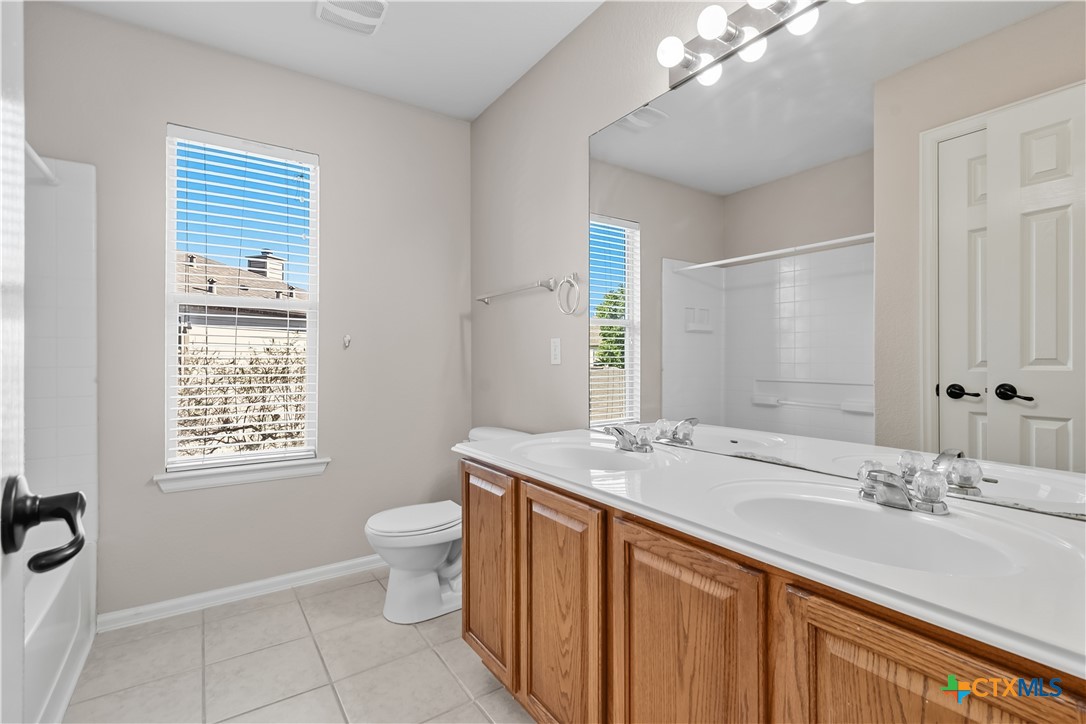 172 Coreopsis Cove Kyle, TX 78640 - Photo 25 of 33 a bathroom with a sink a toilet a mirror and a window