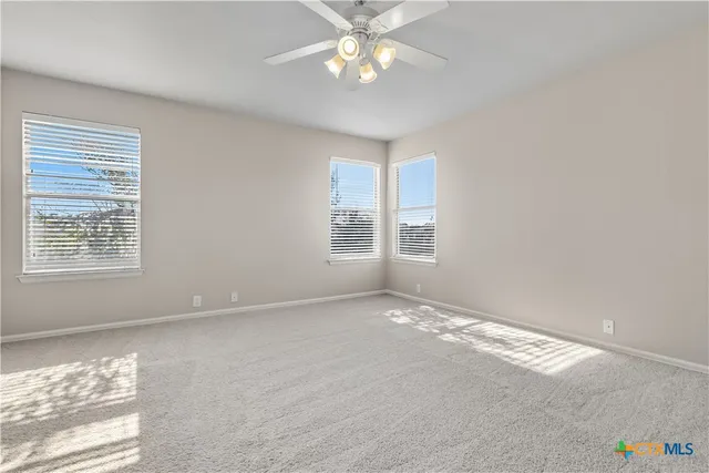 a view of an empty room with window and chandelier fan
