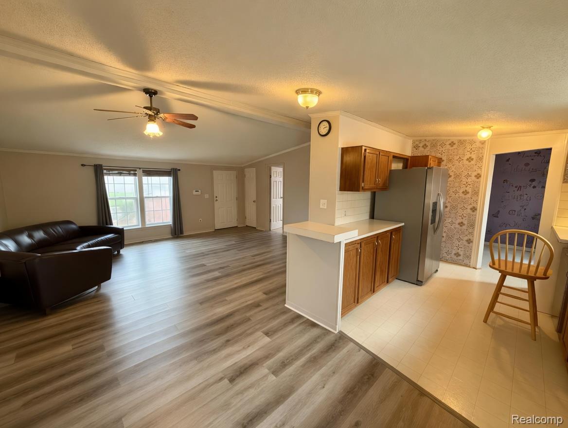 6988 McKean Road Ypsilanti, MI 48197 - Photo 21 of 21 Kitchen featuring light countertops, open floor plan, ornamental molding, stainless steel refrigerator with ice dispenser, and ceiling fan