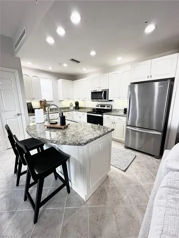 a kitchen with stainless steel appliances granite countertop a refrigerator a stove a sink a table and chairs