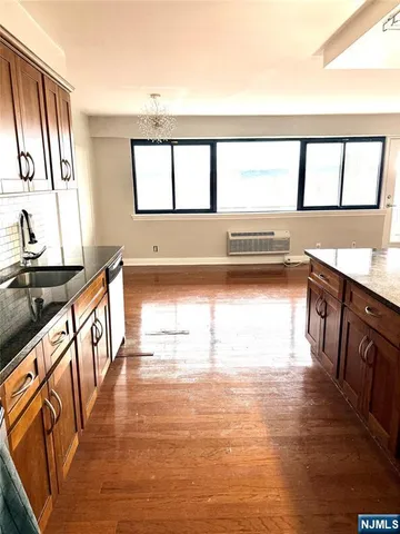 a view of a kitchen with kitchen island a sink wooden floor and a large window
