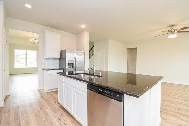 a kitchen with granite countertop a sink cabinets and wooden floor