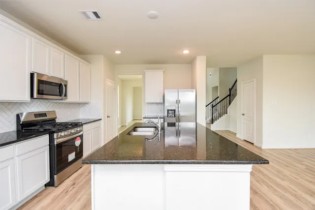 a kitchen with stainless steel appliances granite countertop a sink a stove and microwave