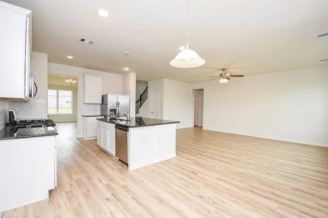 a large kitchen with cabinets wooden floor and stainless steel appliances