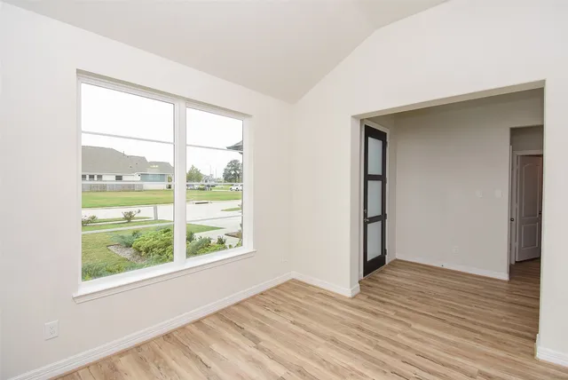 an empty room with wooden floor and windows