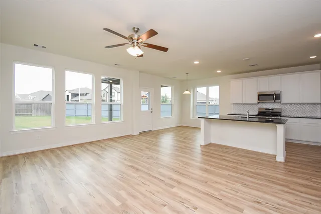 a view of an empty room with window and wooden floor