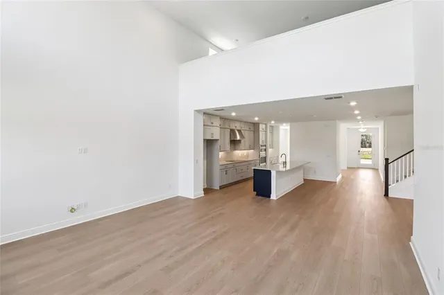 a view of an empty room with wooden floor and stairs