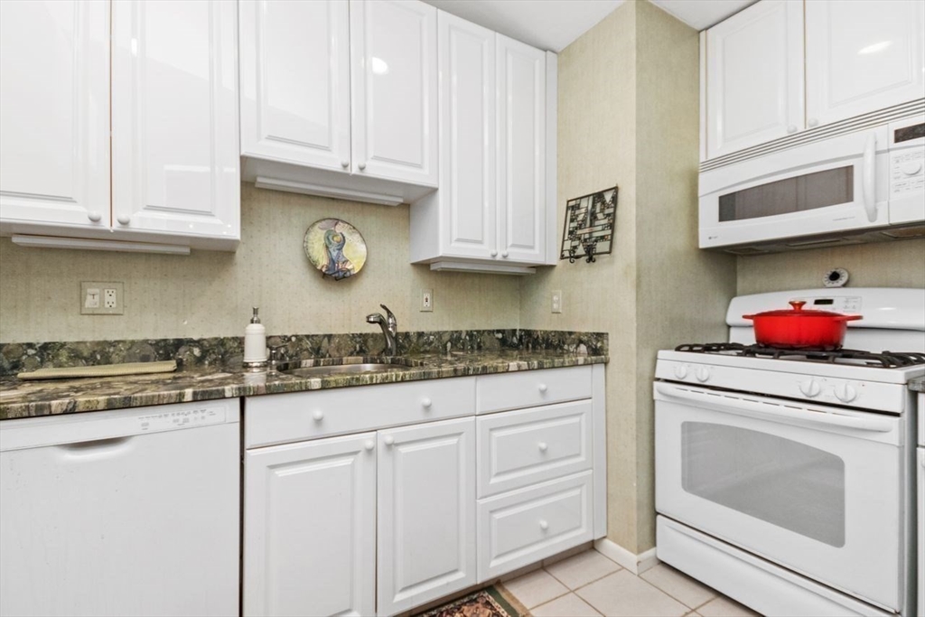 55 Broadlawn Park, Unit 11B Boston, MA 02467 - Photo 11 of 25 a kitchen with granite countertop stainless steel appliances white cabinets sink and a stove
