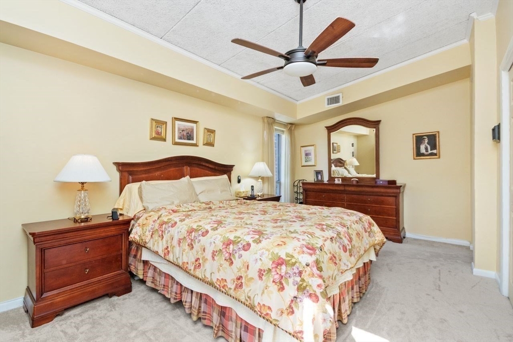 55 Broadlawn Park, Unit 11B Boston, MA 02467 - Photo 14 of 25 a bedroom with a bed and a chandelier