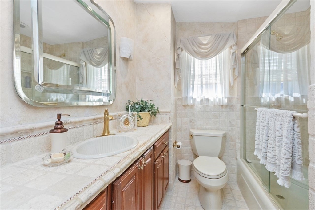 55 Broadlawn Park, Unit 11B Boston, MA 02467 - Photo 16 of 25 a bathroom with a granite countertop sink mirror vanity and toilet