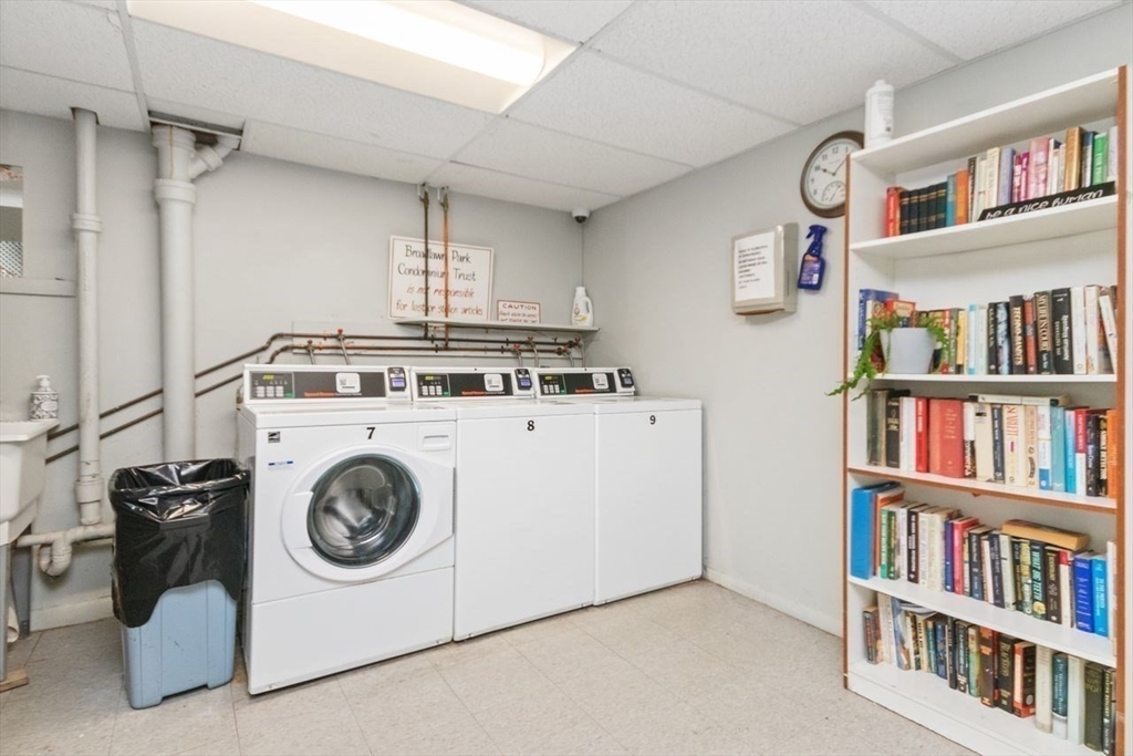 55 Broadlawn Park, Unit 11B Boston, MA 02467 - Photo 19 of 25 a utility room with dryer washer and a book shelf
