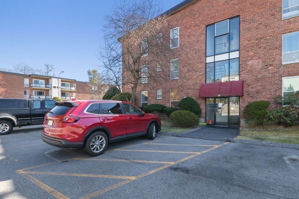 55 Broadlawn Park, Unit 11B Boston, MA 02467 - Photo 24 of 25 a car parked in front of a brick house
