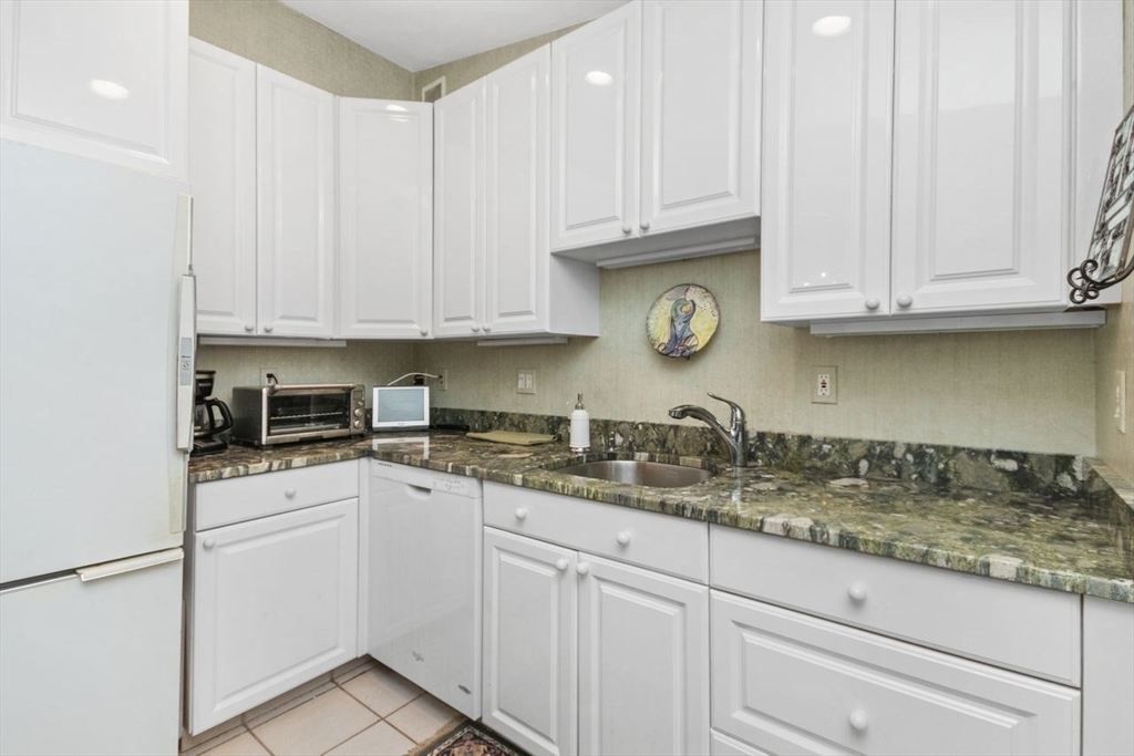 55 Broadlawn Park, Unit 11B Boston, MA 02467 - Photo 10 of 25 a kitchen with granite countertop white cabinets and white appliances