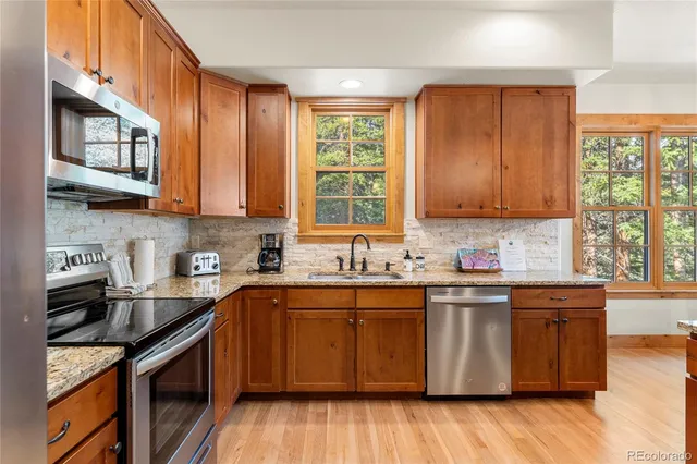 a kitchen with stainless steel appliances granite countertop wooden cabinets a sink and a stove