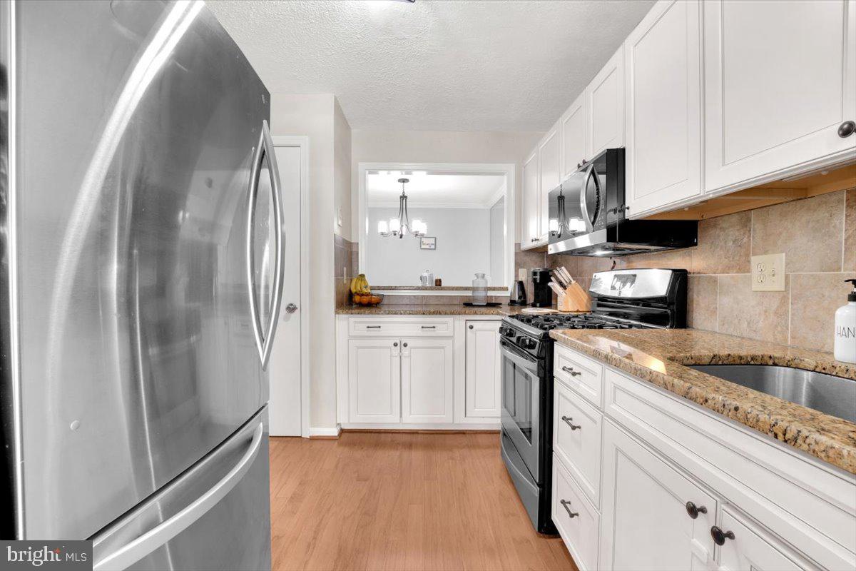10096 Oakton Terrace Road, Unit 10096 Oakton, VA 22124 - Photo 5 of 24 a kitchen with stainless steel appliances granite countertop a refrigerator a stove and white cabinets