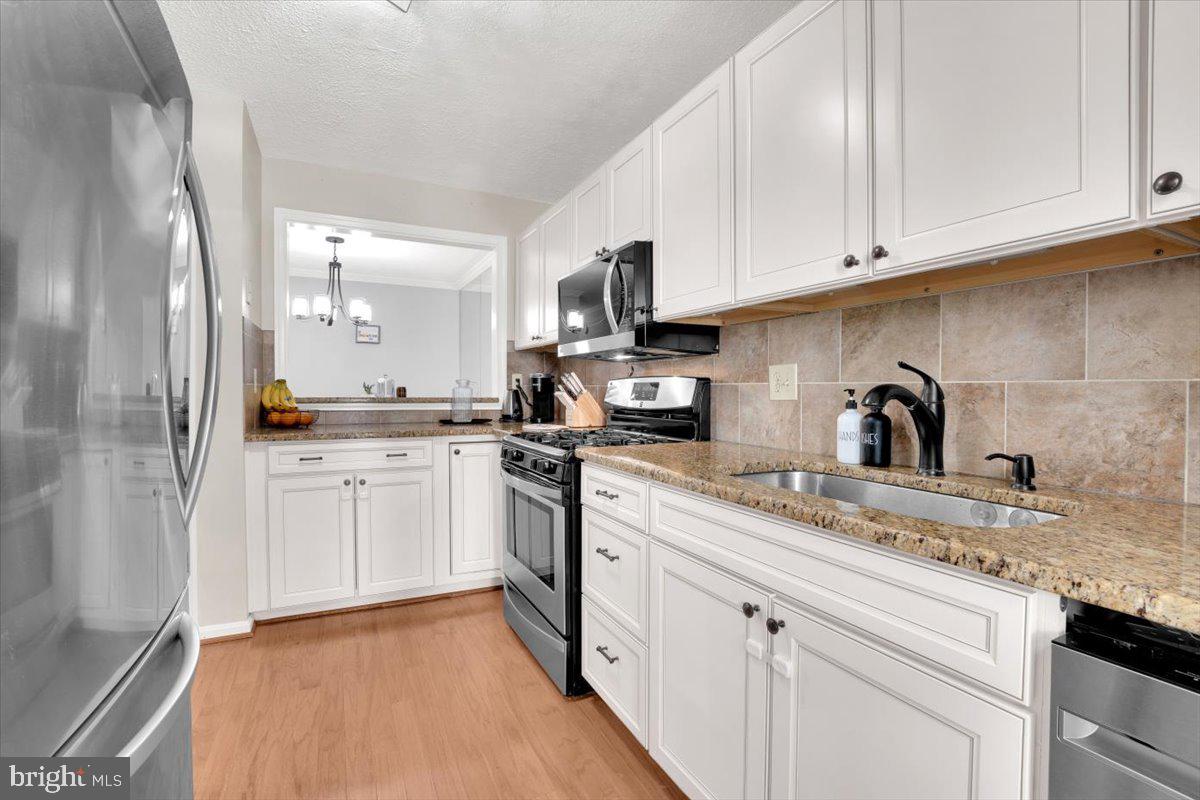 10096 Oakton Terrace Road, Unit 10096 Oakton, VA 22124 - Photo 6 of 24 a kitchen with granite countertop white cabinets and stainless steel appliances