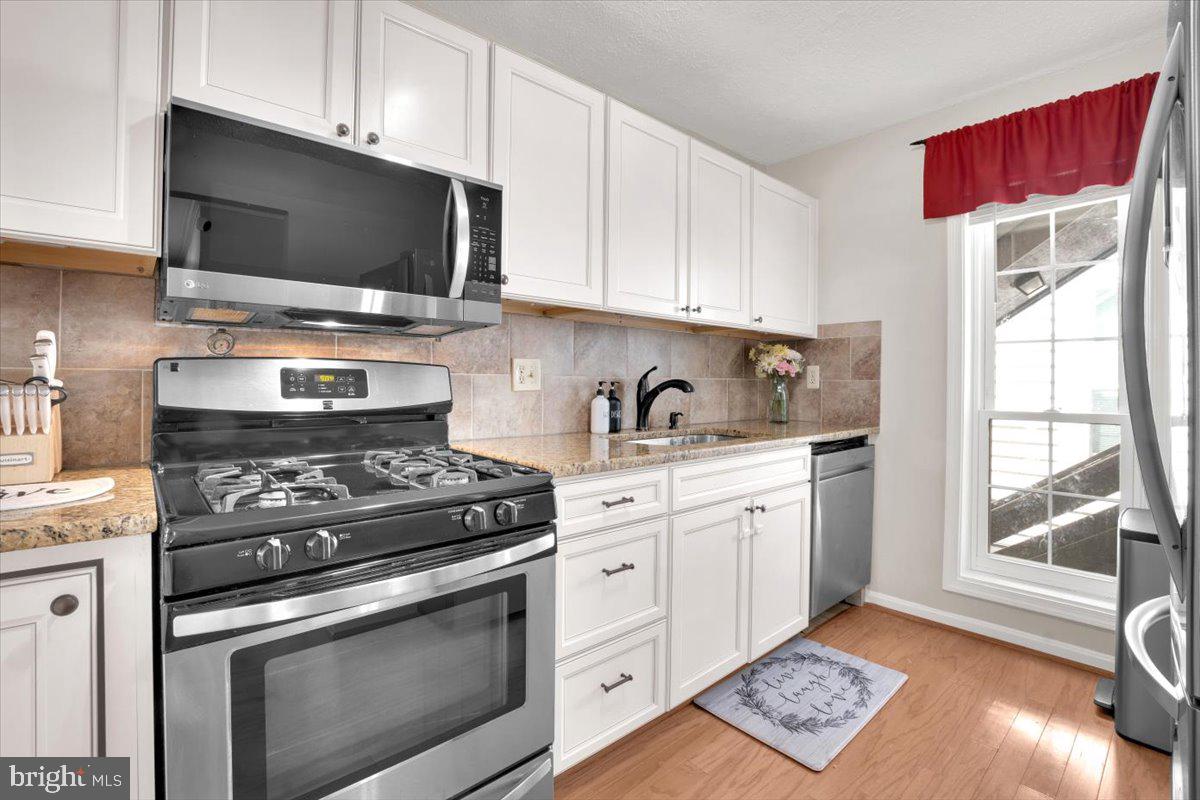 10096 Oakton Terrace Road, Unit 10096 Oakton, VA 22124 - Photo 7 of 24 a kitchen with stainless steel appliances a stove a microwave a sink and cabinets
