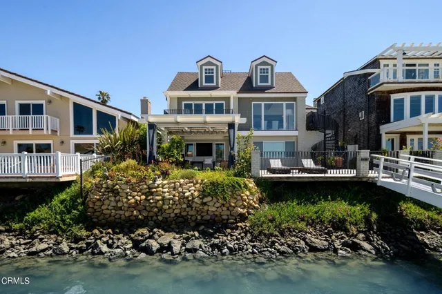 a front view of a house with a garden and lake view