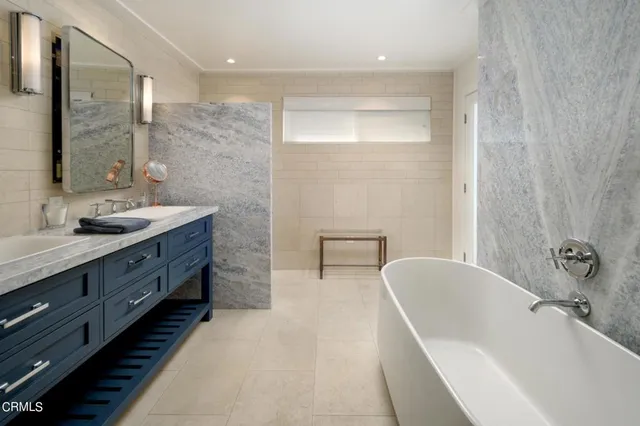 a spacious bathroom with a double vanity sink a mirror and a bathtub