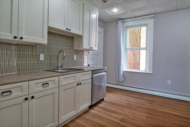 a kitchen with granite countertop white cabinets and a sink