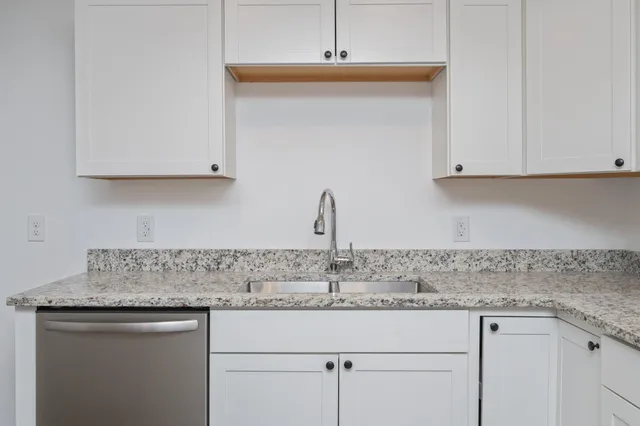a kitchen with granite countertop white cabinets and a sink
