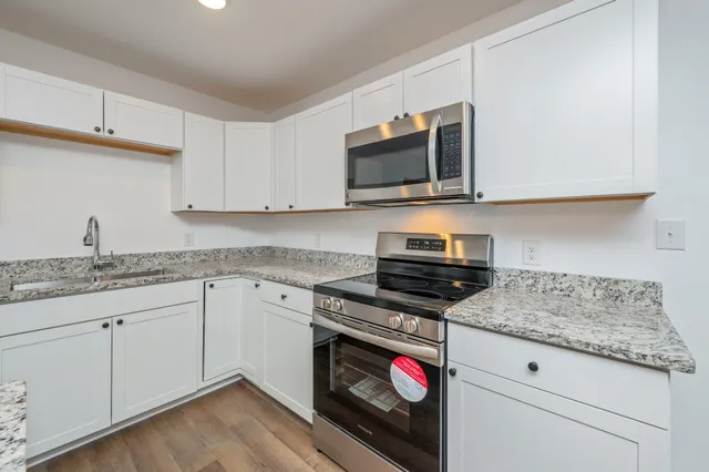 a kitchen with granite countertop a stove sink and microwave