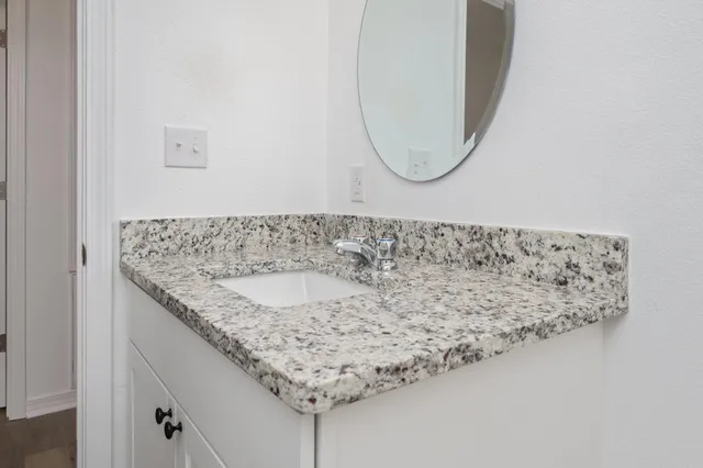 a bathroom with a granite countertop sink and a mirror