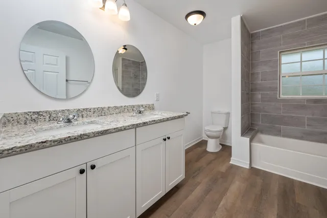 a spacious bathroom with a granite countertop toilet a sink and a mirror