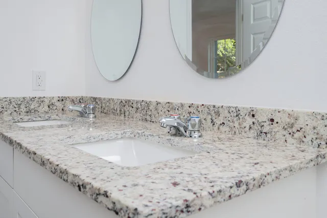 a bathroom with a granite countertop sink and a mirror