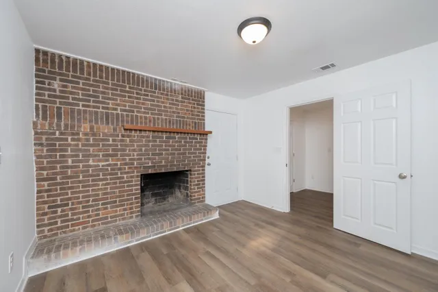 a view of empty room with wooden floor and fireplace