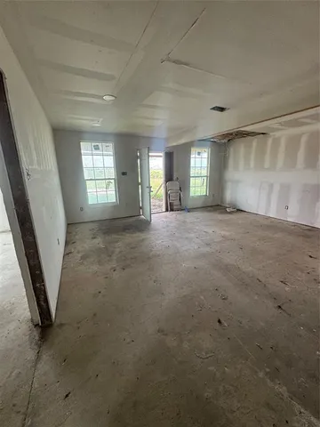 en empty room with windows and fireplace