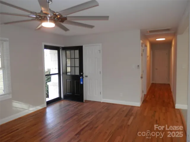 a view of an empty room with window and wooden floor