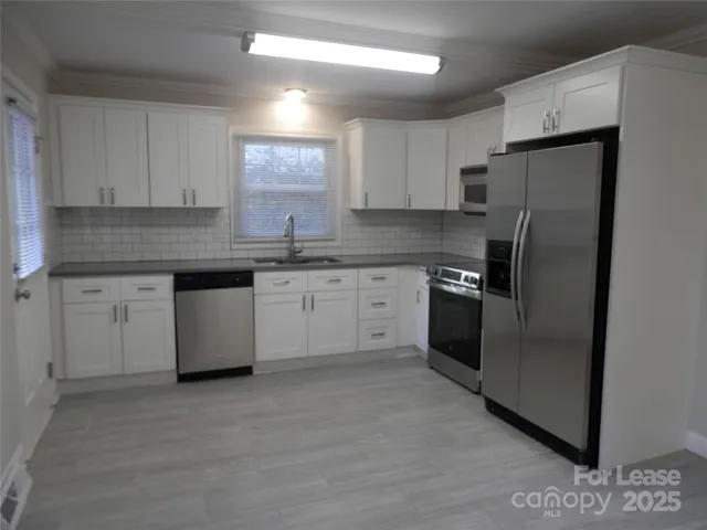 a kitchen with stainless steel appliances granite countertop a refrigerator a sink a stove a refrigerator and white cabinets