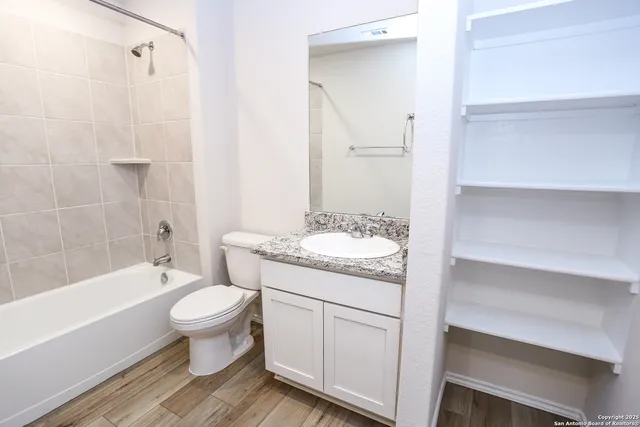 a bathroom with a granite countertop sink toilet mirror and bathtub