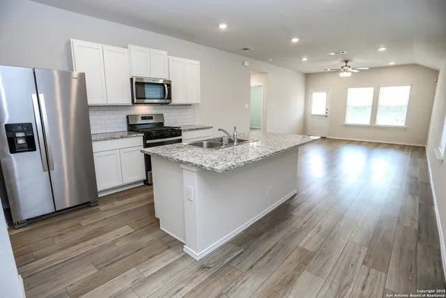 a kitchen with a sink a microwave a refrigerator and cabinets
