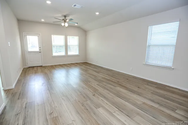 an empty room with wooden floor and windows
