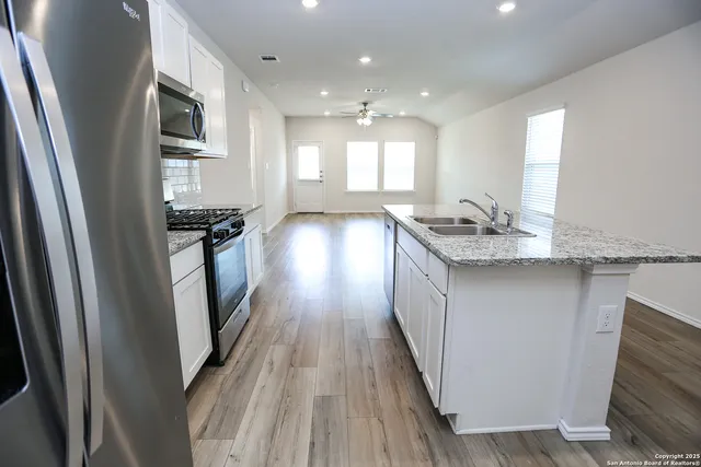 a kitchen with granite countertop a sink stove and refrigerator