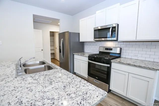 a kitchen with stainless steel appliances granite countertop a sink stove and refrigerator