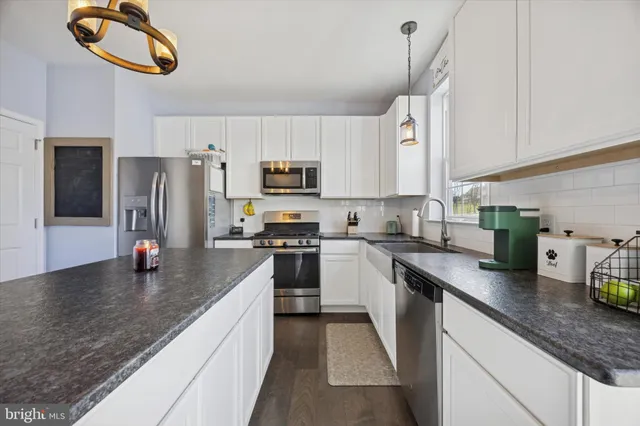 a kitchen with stainless steel appliances granite countertop a sink refrigerator stove and microwave