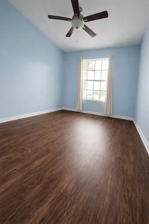 a view of an empty room with wooden floor and a window