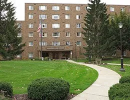 a view of a building next to a big yard and large trees