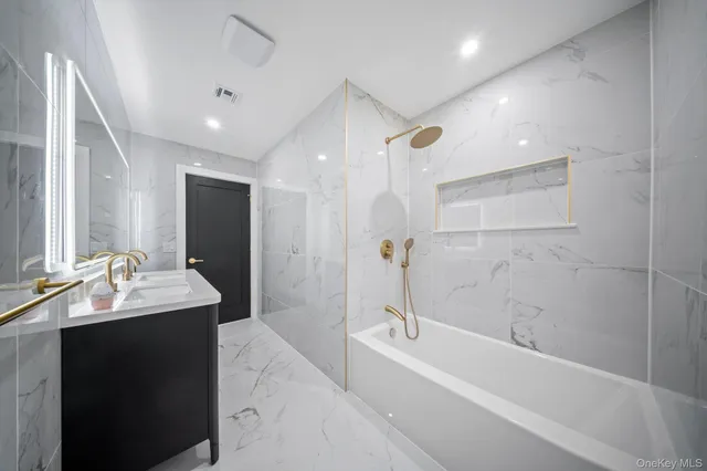 a bathroom with a bathtub shower sink vanity and toilet