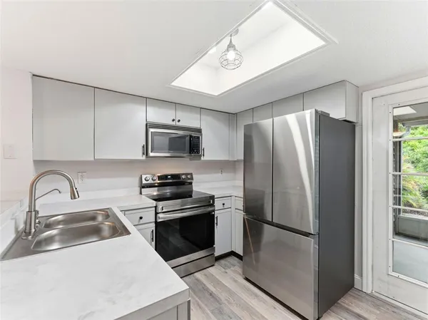 a kitchen with stainless steel appliances granite countertop a refrigerator a sink a stove a microwave and a refrigerator