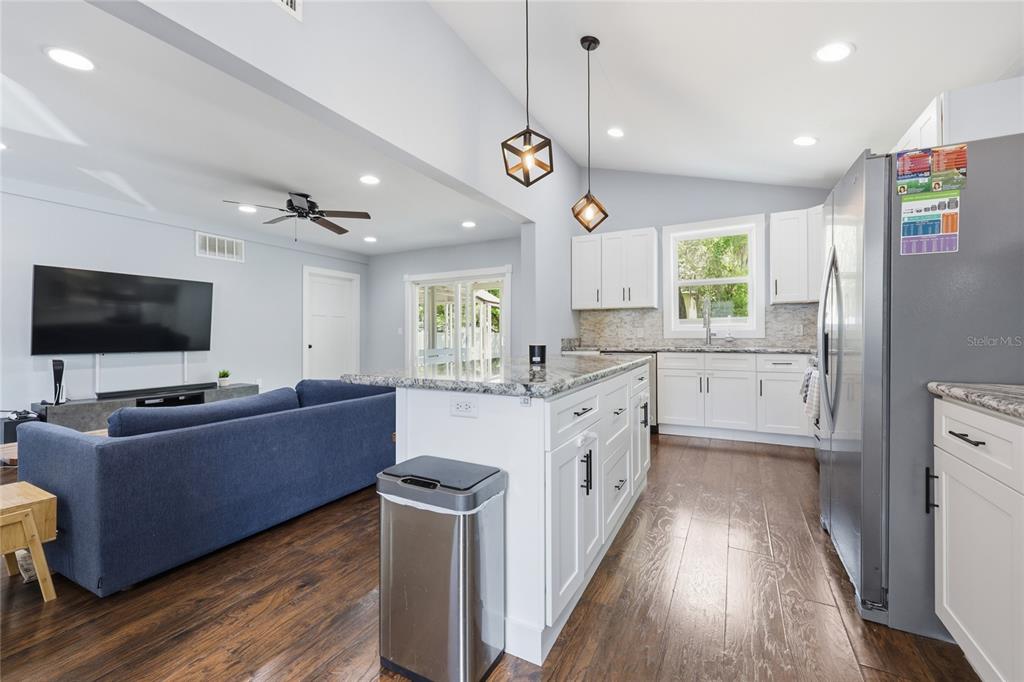 403 Northeast 9th Street Gainesville, FL 32601 - Photo 19 of 62 a kitchen with stainless steel appliances granite countertop a refrigerator a sink dishwasher a oven and a dining table with wooden floor