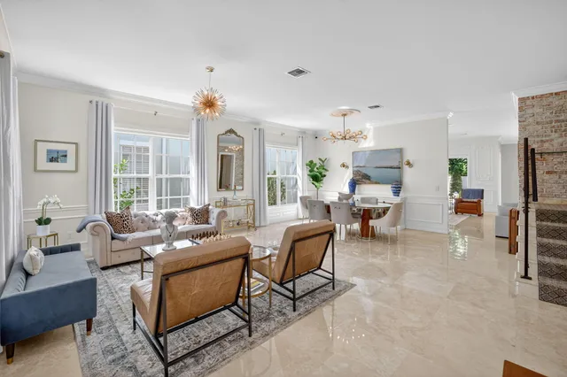 a open kitchen with stainless steel appliances granite countertop a stove top oven a refrigerator a kitchen island a dining table and chairs with wooden floor