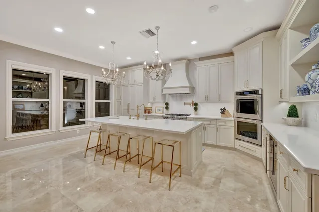 a bedroom with a large bed a chandelier and dresser