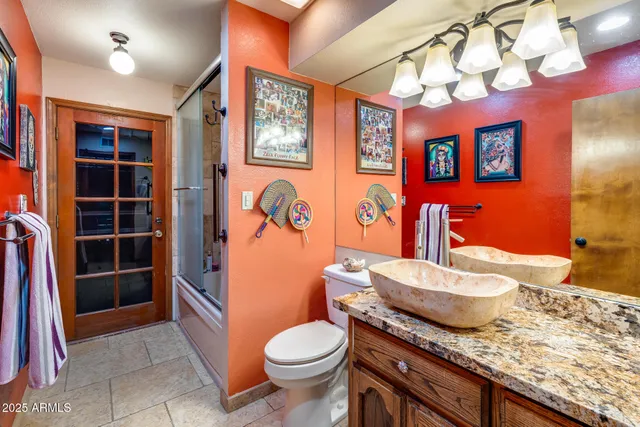 a bathroom with a granite countertop toilet sink and mirror