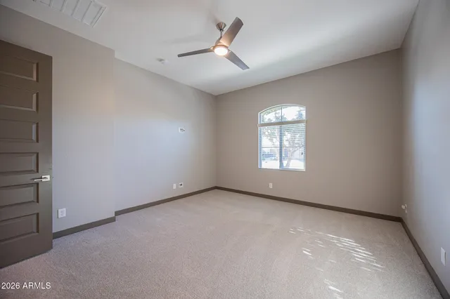 an empty room with ceiling fan and window