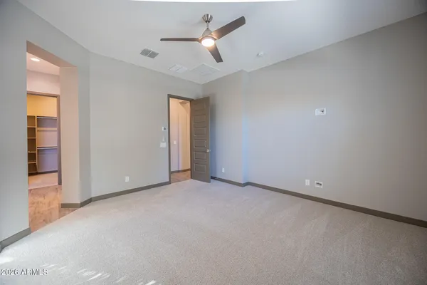 an empty room with closet and a ceiling fan